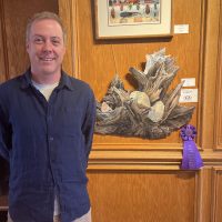 Judge Patrick Berran with the 27th Annual Mollie Fearing Memorial Art Show Best In Show Piece _Beach Finds_ by Tom Dean. Photo courtesy of Dare Arts.