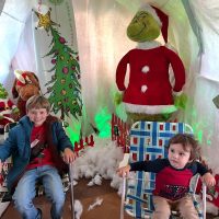 Local children posing with the Grinch at the Broken Candy Cane last year. Photo courtesy of Tatum Clements.